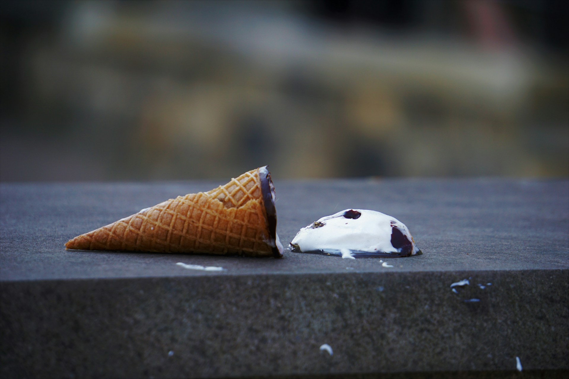 Cono gelato caduto a terra, con la parte cremosa che si sta sciogliendo.