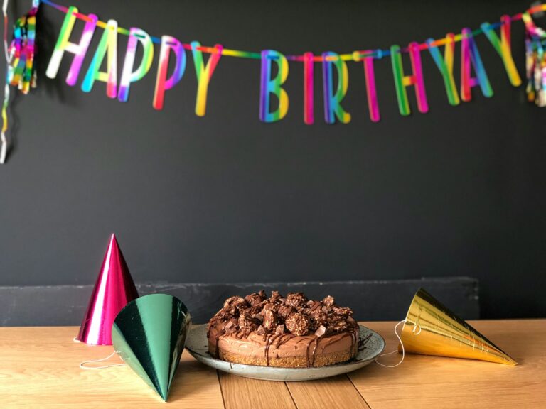 Torta al cioccolato appoggiata su un tavolo. In alto un festone con scritto Happy Birthday.